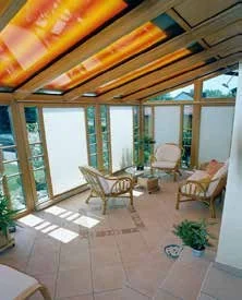 Wintergarten mit orangefarbener Dachbeschattung und Korbmöbeln