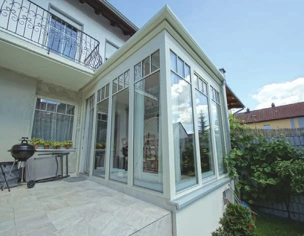 Weißer Glasanbau mit Walmdach an einem Wohnhaus